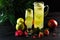 Green apple lemonade with lime in a jug and glass and fruits on a dark background