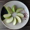 Green apple Malus domestica slices on white plate isolated on wallpaper background closeup.