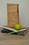A green apple. a paper lunch bag and a stack of books