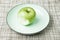 Green apple on plate, missing bite