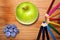 Green apple, rainbow pencils and blueberries on wooden desk