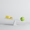 Green apple sitting on seesaw with cheese on opposite end on white background