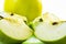 Green apple sliced in four pieces and an apple on a white background