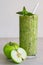 Green apple smoothie in a glass, whole and half apple