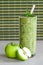 Green apple smoothie in a glass, whole and half apple