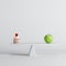 Green apple tipping on seesaw with green apple on opposite end on white background