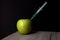 Green apple on a wooden board with syringe inside