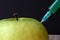 Green apple on a wooden board and syringe inside