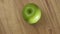 Green apple on wooden plate
