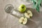 Green apples ang glass of water on beige table, minimalist spring summer composition, copy space