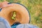 Green apples collected in a large straw hat in the hands of a farmer on a background of green grass, harvesting homemade apples,