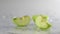 Green apples fall in water super slow motion