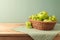 Green apples and grapes in basket on wooden table with tablecloth. Kitchen background