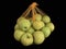 Green apples in a grid isolated on black. Ripe fruits in a string bag. Apples with face pattern. Concept: joy, happiness, positive