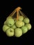 Green apples in a grid isolated on black. Ripe fruits in a string bag. Apples with face pattern. Concept: joy, happiness, positive