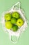 Green apples in a net bag on a green background. Green monochrome. Vertical format