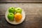 Green apples and orange on wooden plate, fruits on wooden disk