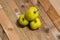 Green apples on a wooden rough structured top shot from an angle above laying next to a kitchen window cascading daylight insight