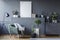 Green armchair between black lamp and plants in grey flat interior with mockup of poster. Real photo