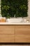 Green artificial plants, vanity and different personal care products in bathroom