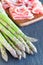 Green asparagus and bacon on a dark slate background, ingredients for healthy appetizer, vertical