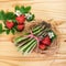 Green asparagus with strawberries. Healthy vegetables over bright wood.