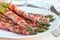 Green asparagus wrapped with bacon on  white plate, horizontal