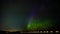 Green aurora northern light dancing under a starry and moonlit sky on a frozen lake in a nordic country