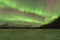 Green Aurora Over Mountains And A Frozen Lake