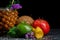 Green avocado, brown coconut, orange pineapple. Mint, flowers and carambola. Close-up of fruits on a black background.