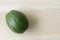 Green avocado on the wooden floor. Fresh avocado on the wooden table