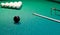 On a green background of a billiard table, white balls are lined with a triangle with a cue for playing