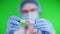 Green background. close-up, doctor`s hands in blue medical gloves holds test tube with inscription virus. doctor wearing