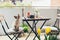 Green balcony decorated with a lot of plants and spring flowers. Beautiful new outdoor furniture wooden - table and chairs. Having