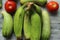 Green banana, cucumber and tomato display with selective focus.