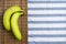 Green banana placed on brown bamboo mat over white table cloth with stripe.