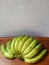 green bananas still raw on a brown table