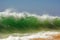 A green beachbreak wave over sky