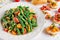 Green beans salad with Red, Yellow Tomatoes, bruschettas and flaked almond on white plate