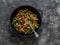 Green beans, sweet peppers, carrots, onions, green peas stir fry in a pan on a dark background, top view. Fast diet vegetarian