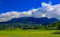 Green, beautiful and charming farmland and majestic mountains in the distance with spectacular cloudscape