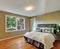 Green bedroom interior with hardwood floor and queen size bed.