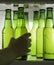 Green beer bottles chilled in drops of water on a shelf in the refrigerator. Hand takes the bottle