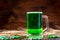 Green beer in a glass mug with gingerbread clover, horseshoe, wheat spike and gold coins on a rustic wooden surface. Festive