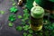 Green beer pint and leprechaun hat over dark green background, decorated with shamrock leaves