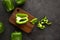 green bell peppers on wooden cutting board on black and dark grey background. Green pepper sliced and chopped on wooden chopping