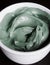 Green bentonite clay in the white bowl. Diy facial mask and body wrap recipe. Clay texture close up. Natural beauty treatment