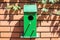 green bird house on brick wall