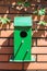 green bird house on brick wall