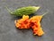 Green bitter gourd and overripe orange fruit, split apart